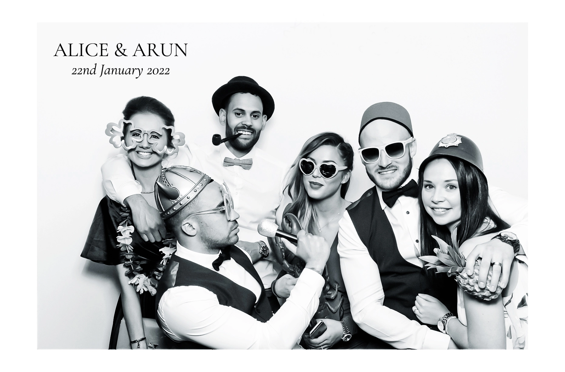A group of friends in black and white, dressed in costumes and party props, titled 'Alice & Arun, 22nd January 2022'.